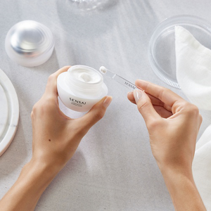 Person holding open jar of Comforting Barrier Mask in one hand and a spatula in the other hand